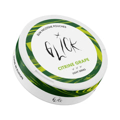 Front-angled tilted view of Glick Citrine Grape Slim Nicotine Pouches, Light Series. The can features a white lid with vibrant green and yellow accents encircling the design, highlighting the refreshing 'Citrine Grape' flavour. The Glick logo and 'Slim Nicotine Pouches' branding stand out, with three light intensity markers indicating the 4mg nicotine strength. The side includes a 'Made in Europe' label, emphasizing quality craftsmanship.