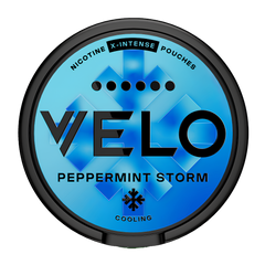 A round black-lidded can of Velo Peppermint Storm cooling nicotine X-Intense Pouches, featuring a bright blue and cyan geometric design on the label.