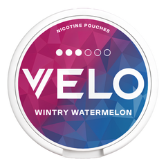 A round nicotine pouch can with a white plastic rim and a colorful geometric label. The label features a faceted polygon pattern transitioning from magenta-pink to purple and blue, with the brand name 'VELO' in large white letters and the flavor 'WINTRY WATERMELON' printed below.